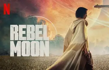 Promotional image for the Netflix film "Rebel Moon" featuring a brunette woman, clad in a light-colored hooded robe, standing in a golden field. She is facing right with a serious expression. Imposing planets, one with a ring, loom in the background sky. The “Rebel Moon” film title is overlaid in white text. The red Netflix logo is at the top left.