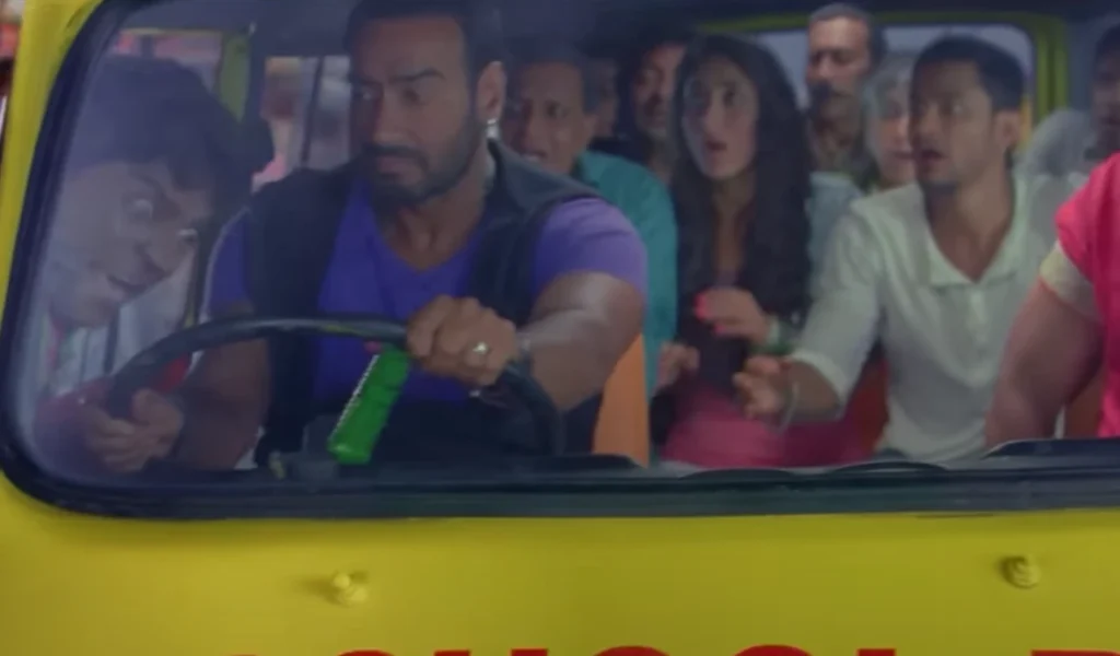 A scene from the movie "Golmaal 5" showing Ajay Devgn driving a yellow school bus, with passengers exhibiting expressions of fear and surprise.