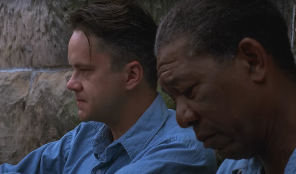 Close-up of characters Andy Dufresne and Ellis Boyd Redding, faces etched with concern, in a scene from The Shawshank Redemption, one of the top movies for US and UK audiences.