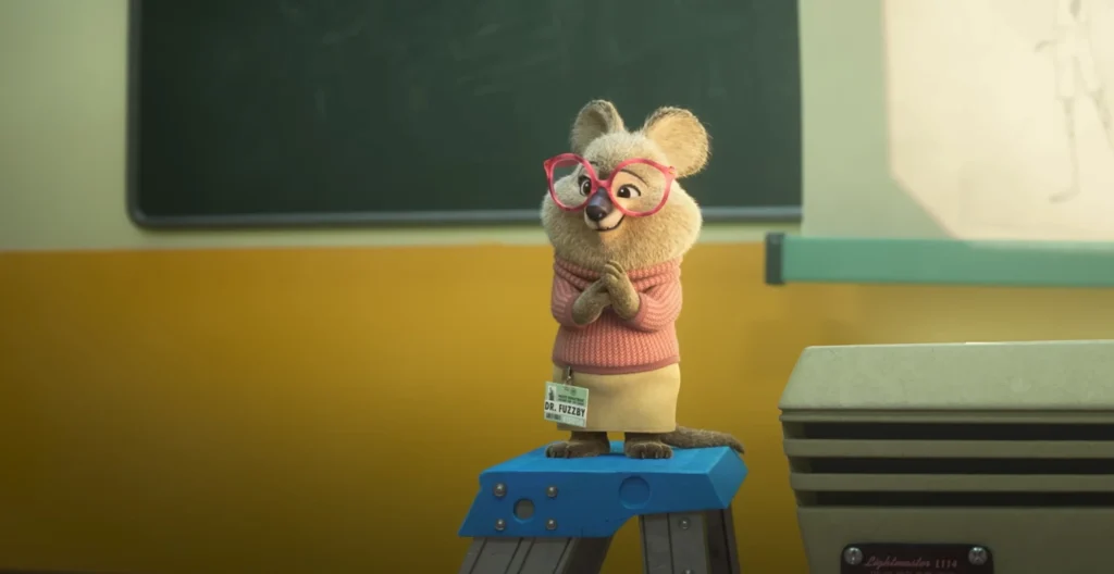 Dr. Fuzzby, a beige rodent-like character with pink glasses, stands on a blue step-stool and smiles with hands clasped, from "Zootopia 2 Trailer".