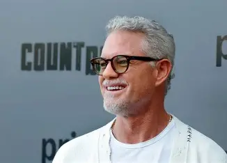 A side profile of Eric Dane smiling and wearing tinted glasses and a white cardigan at the Prime Video Countdown premiere.